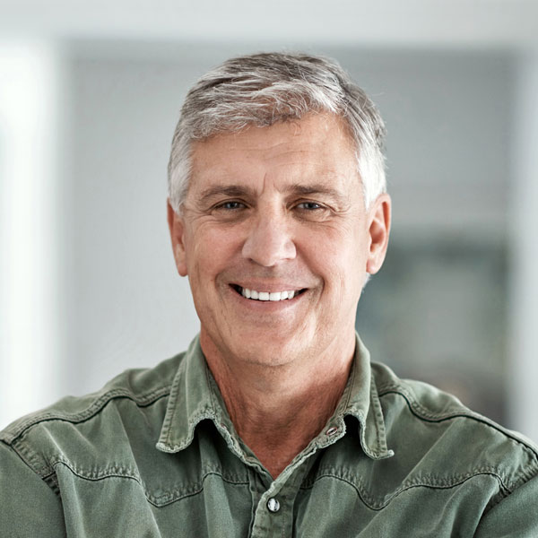mature man standing with his arms crossed at home